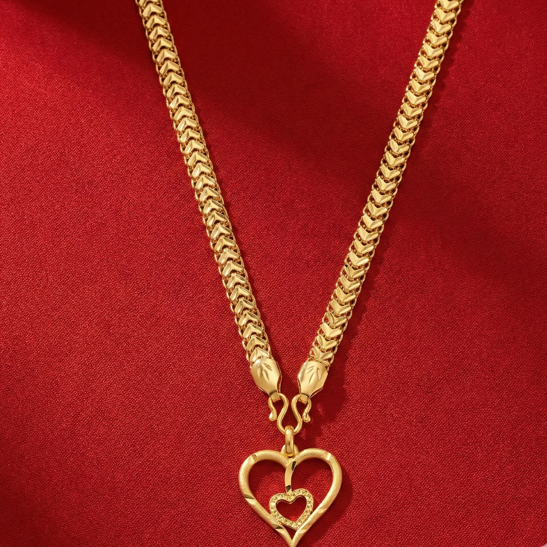 Gold necklace with a heart-shaped pendant on a red background