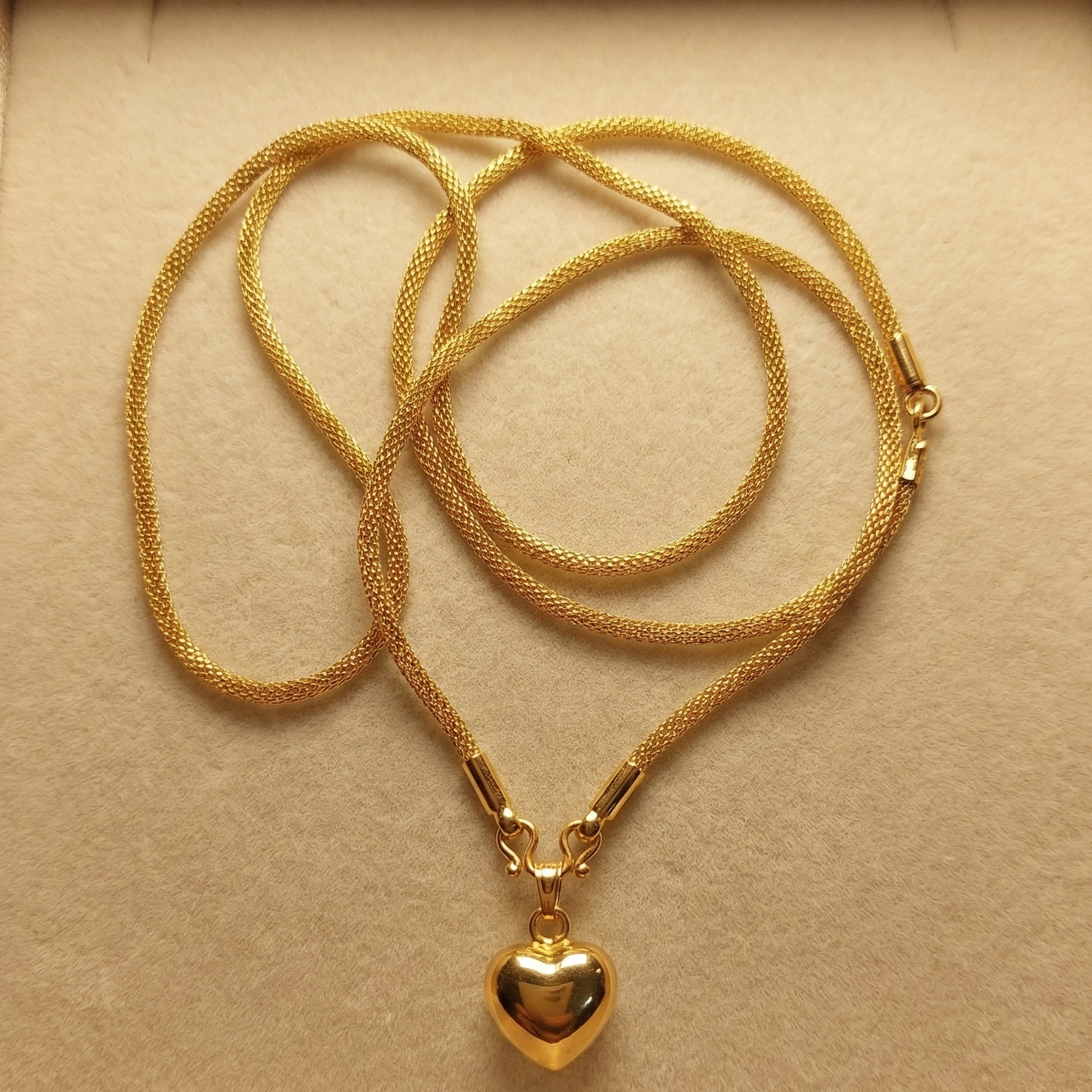 Gold necklace with a heart pendant in a beige box