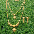 Gold heart-shaped necklace and earrings on green grass