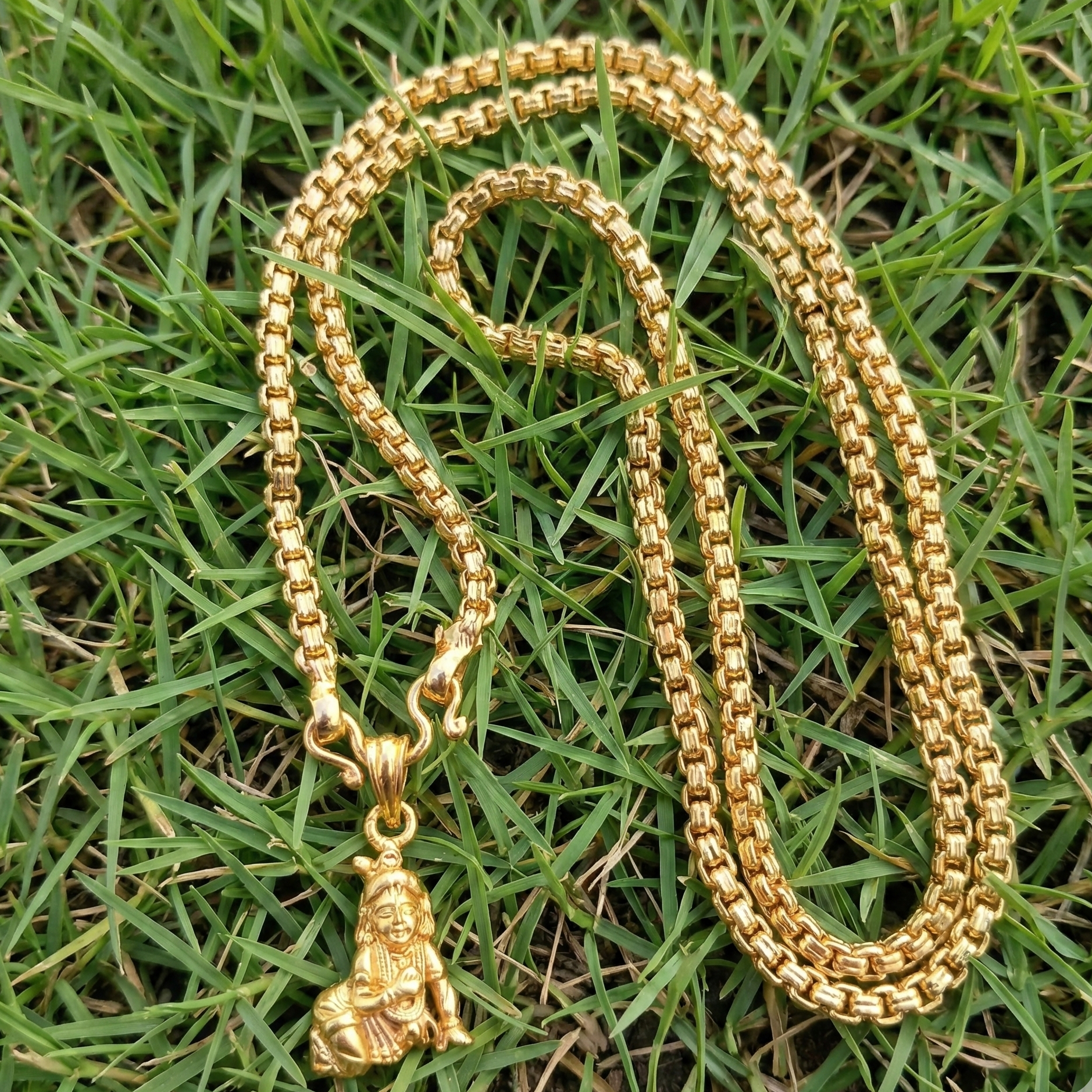 Gold chain necklace with a pendant on grass